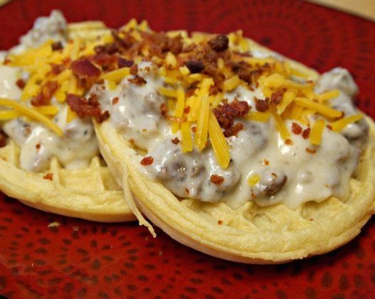 two waffles covered in cheese and bacon on a red plate with gravy