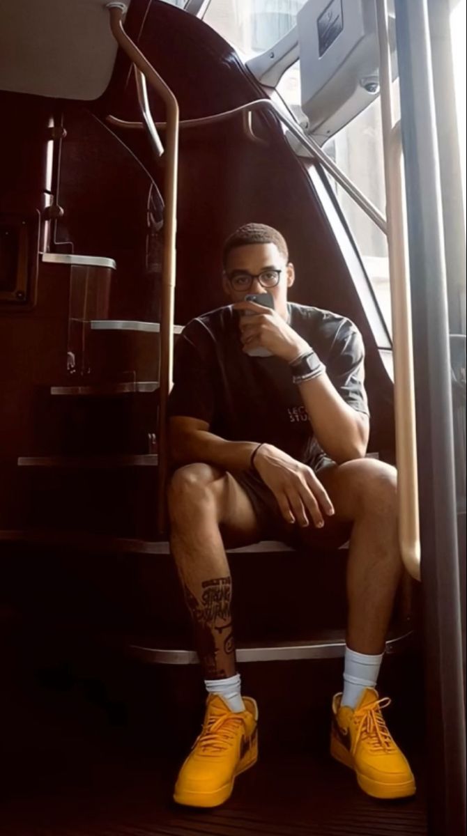 a man sitting on top of a set of stairs with his feet up and wearing yellow shoes