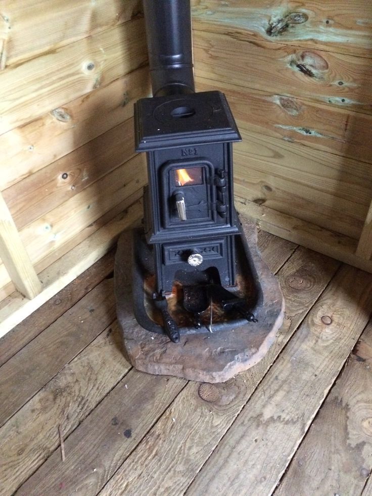 a wood stove sitting on top of a wooden floor next to a pile of logs