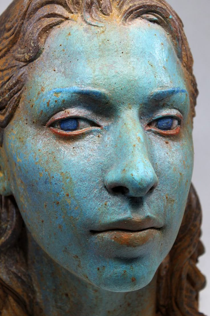 a close up of a statue of a woman's face with blue paint on it