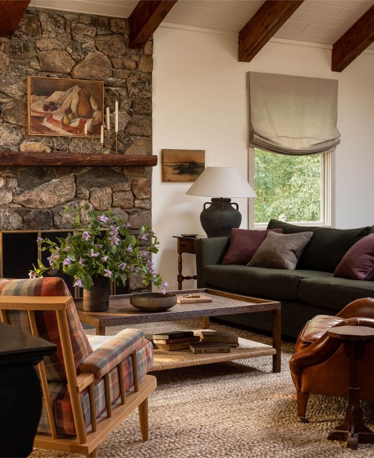 a living room filled with furniture and a fire place in front of a stone wall