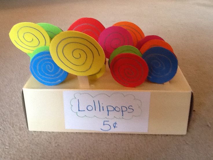 a display box with colorful lollipops on it's sides and a sign that says 5 o'clock