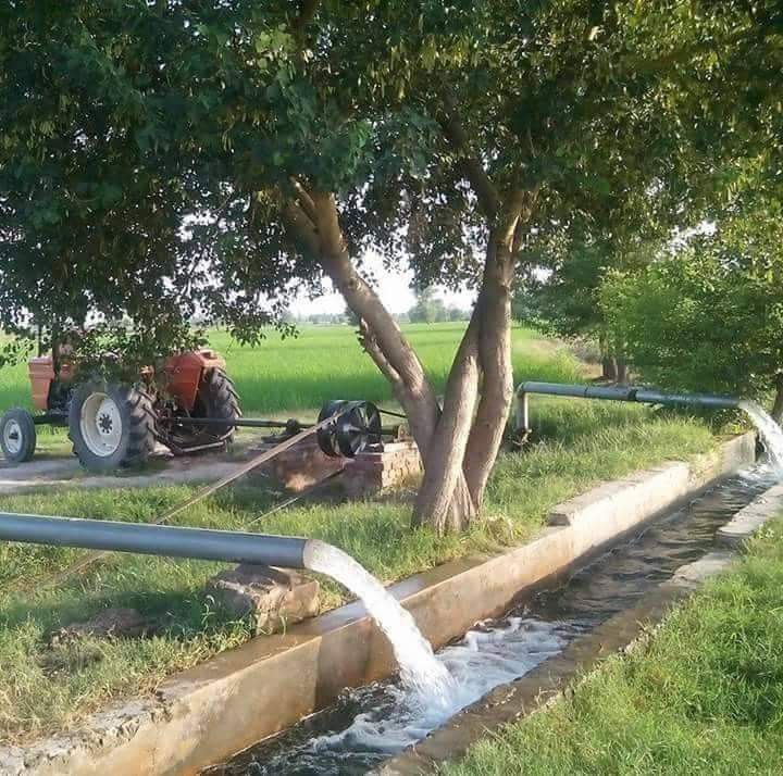 a tractor is parked next to a tree and water spewing from the hose