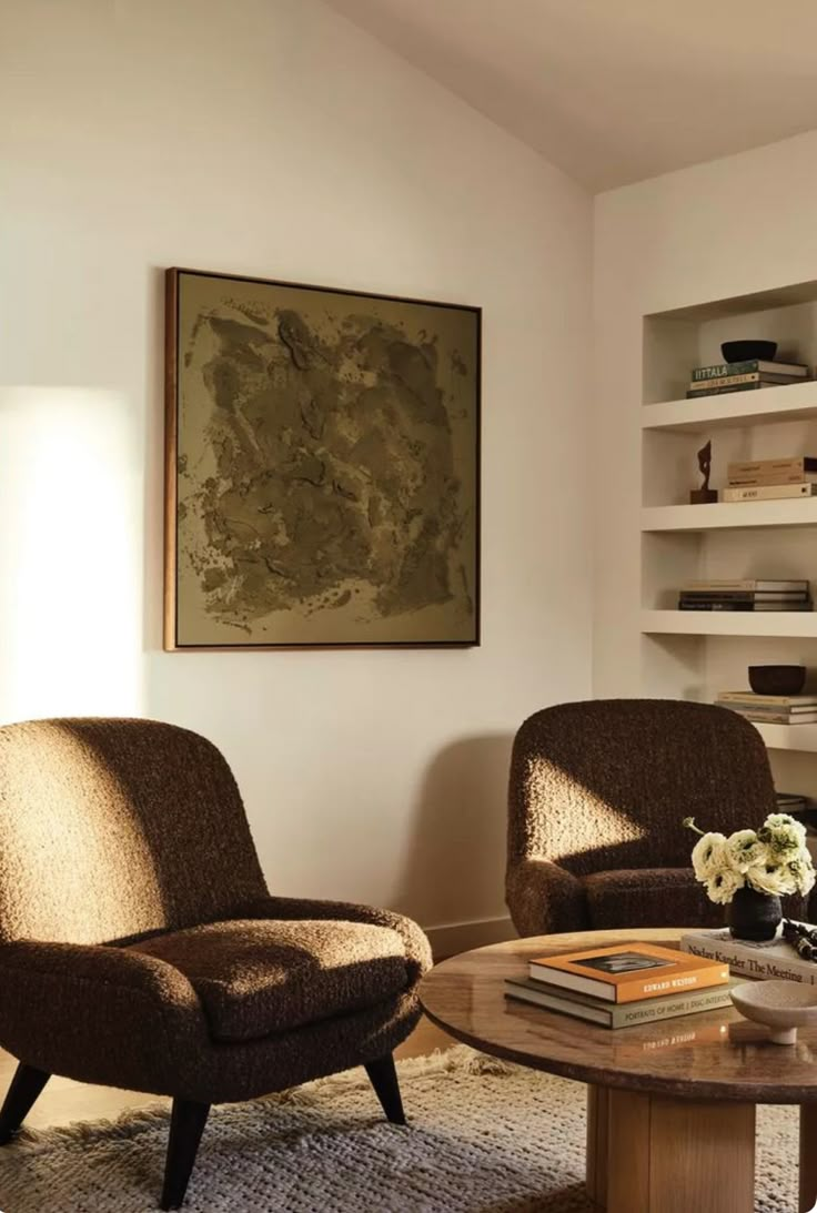 a living room with two chairs and a coffee table in front of a book shelf