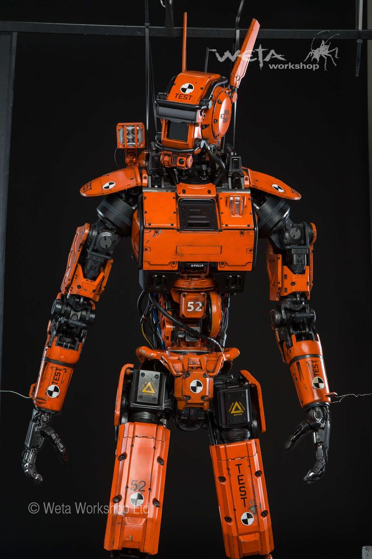 an orange and black robot is standing in the dark