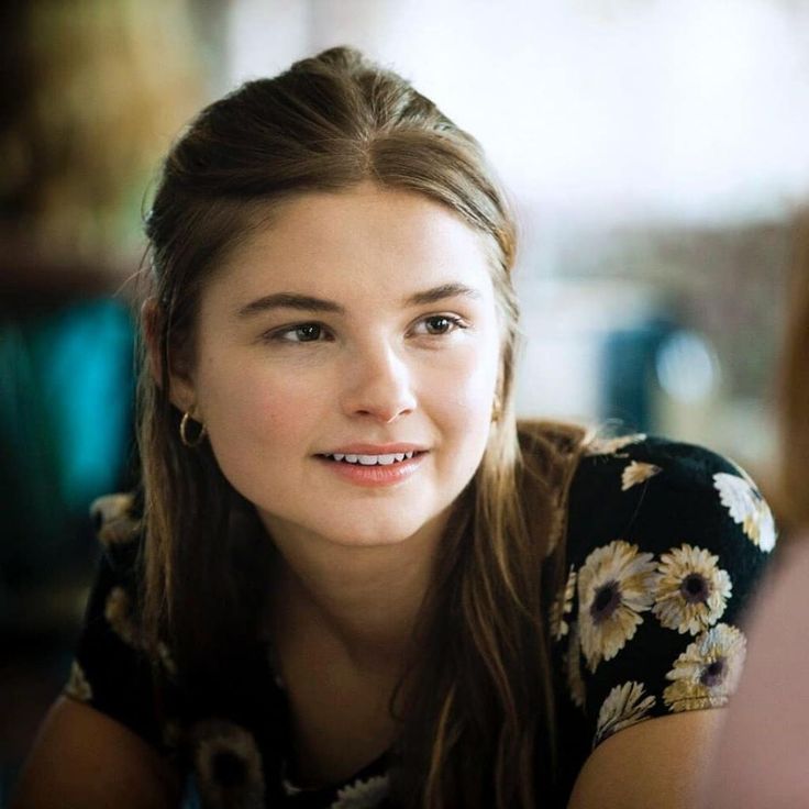 a young woman is smiling and looking at the camera while sitting in front of her