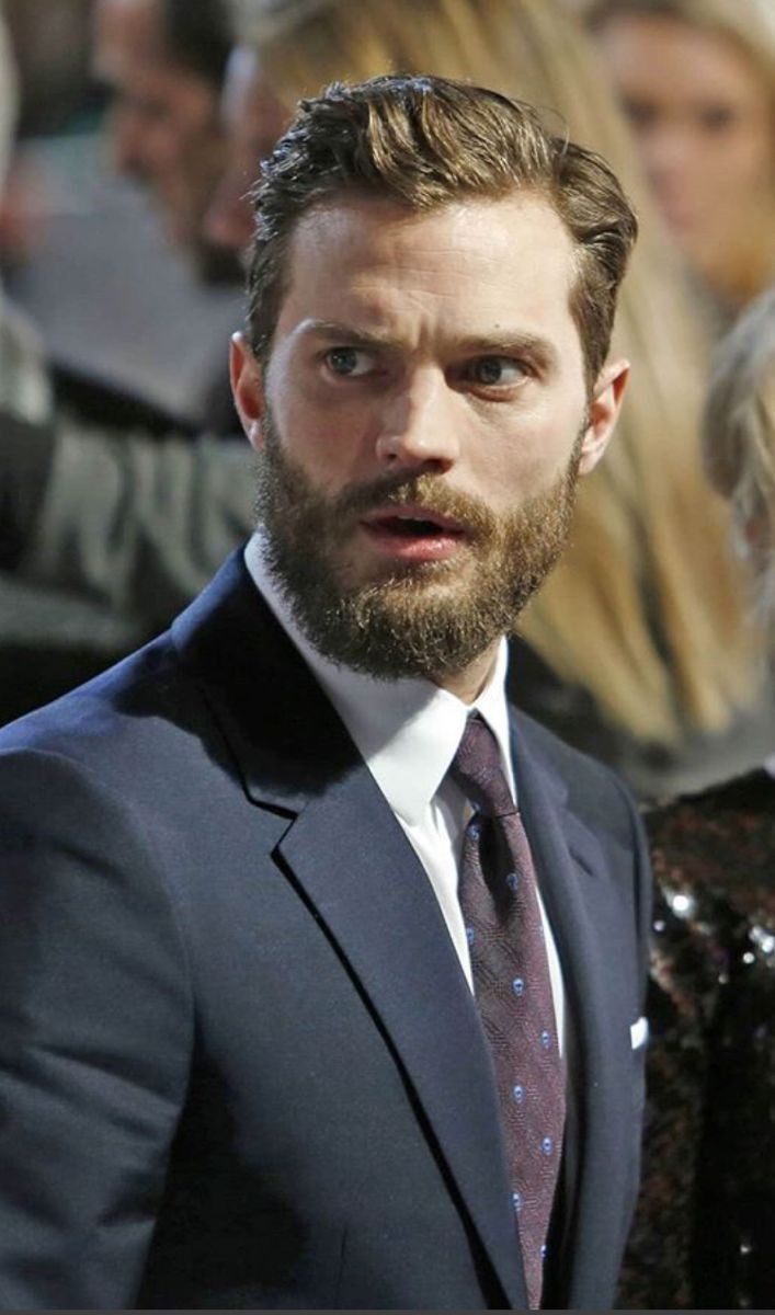 a man in a suit and tie looking at the camera with other people behind him