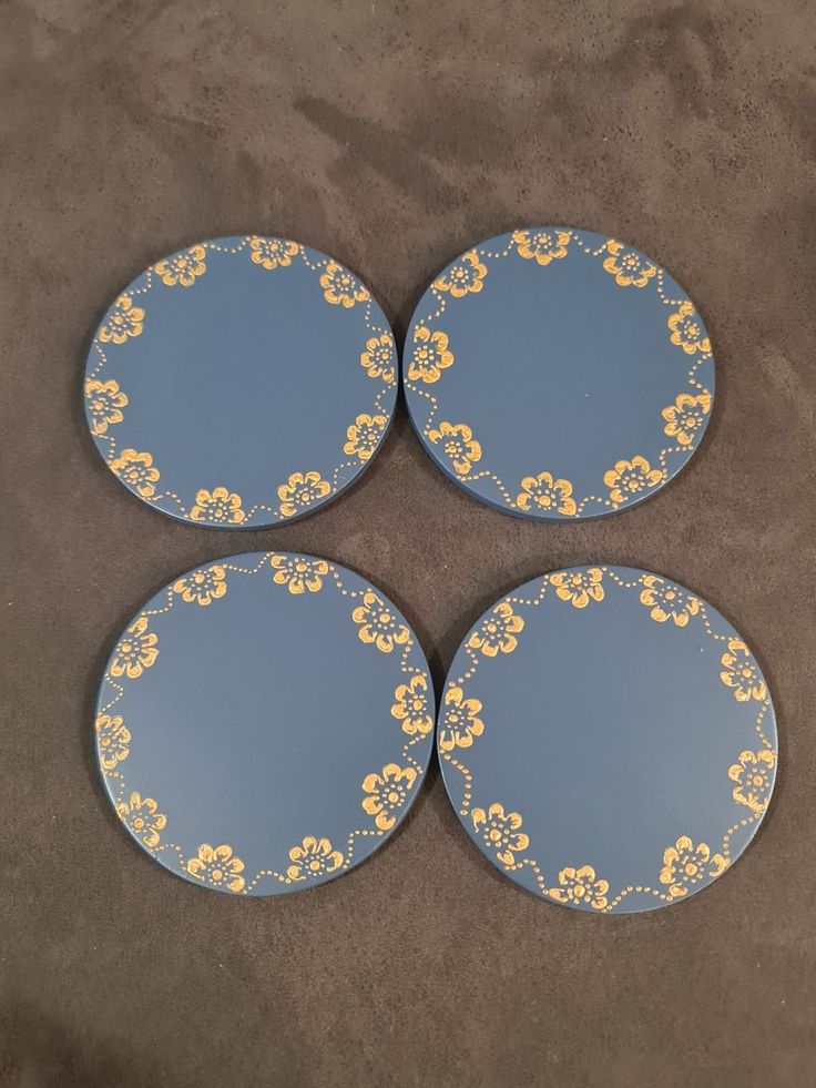 three blue and yellow plates with flowers on them sitting on the ground next to each other