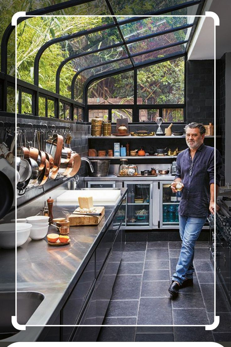 a man standing in a kitchen next to an oven and counter top with pots and pans on it