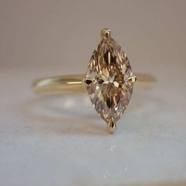 a fancy yellow diamond ring sitting on top of a white countertop next to a wall