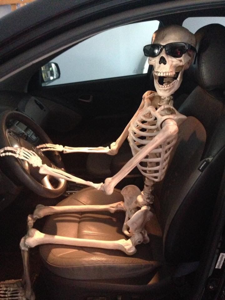 a skeleton sitting in the driver's seat of a car