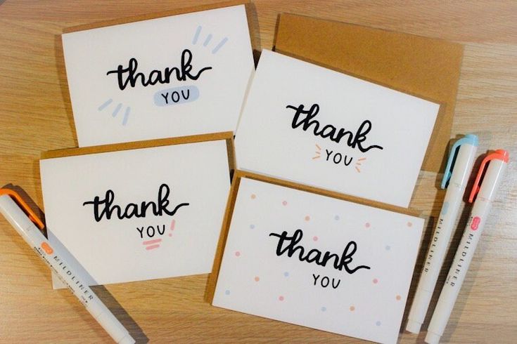 four thank you cards with markers and pens on a wooden table next to each other