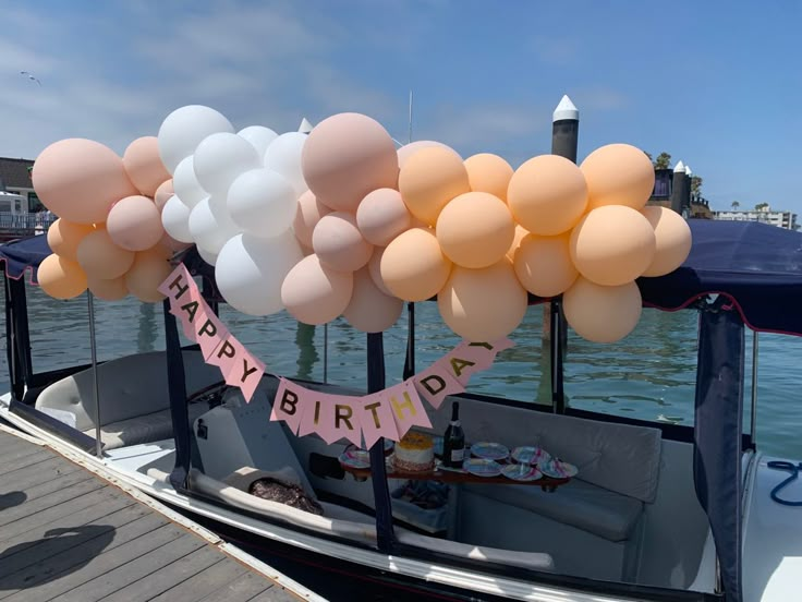 there is a boat with balloons on it and a sign that says happy birthday hanging from the front