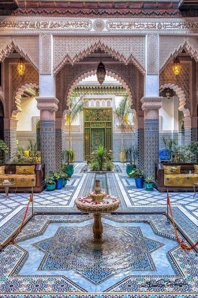 the inside of an ornate building with colorful tilework and potted plants on either side