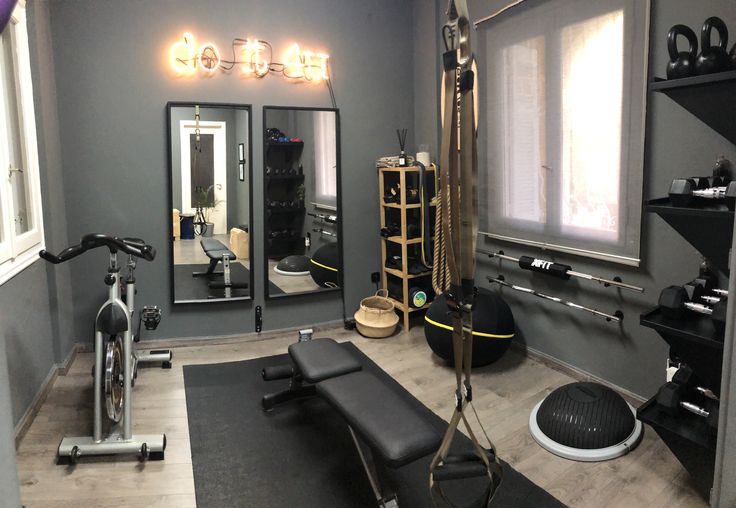 a gym with exercise equipment and mirrors in the corner, along with lights on the wall