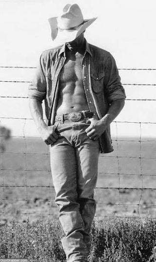 a shirtless man wearing a cowboy hat standing in front of a fence