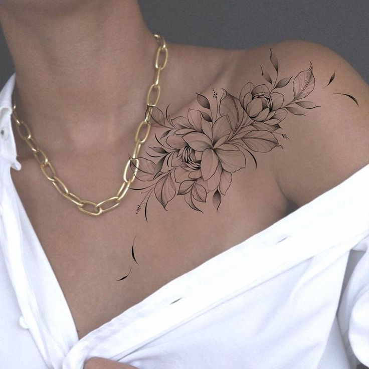 a woman's chest with flowers on it and a gold chain around her neck