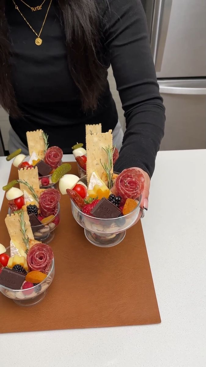 a woman sitting at a table with some fruit and crackers in small bowls on it