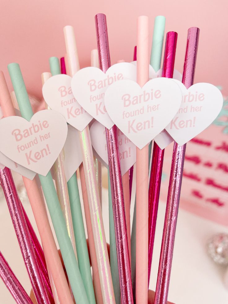 several heart shaped straws in a cup with pink and green handles, on a table