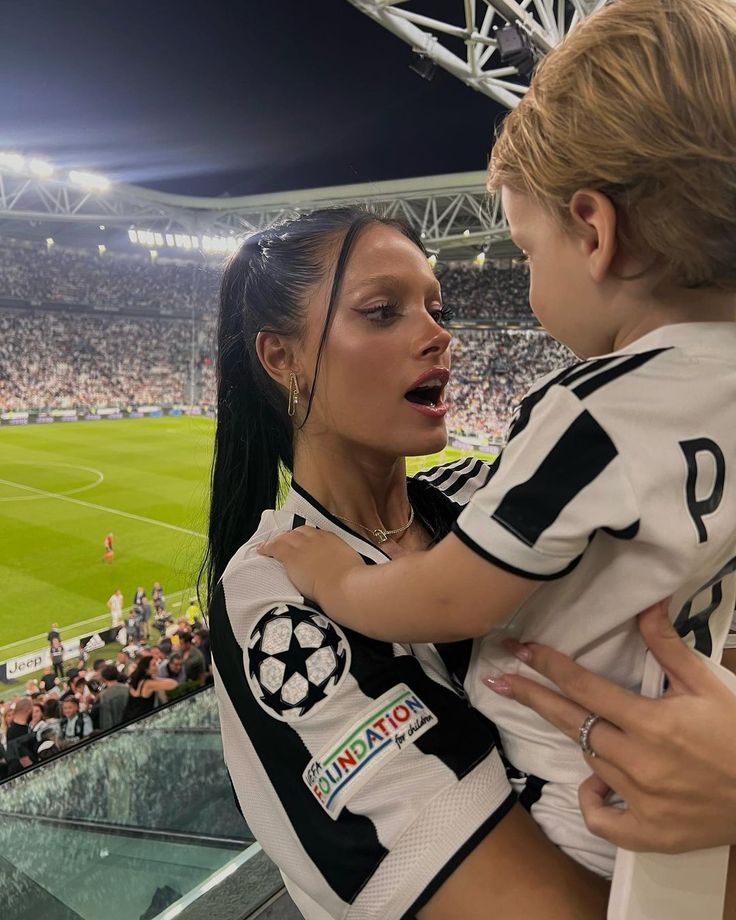 a woman holding a child at a soccer game