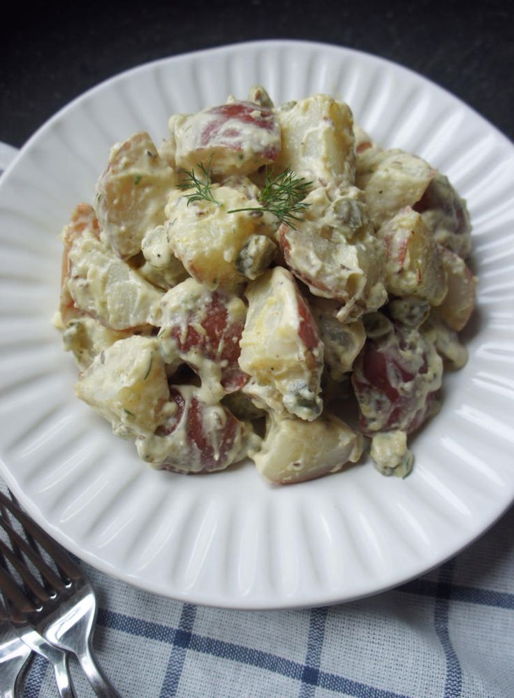 a white plate topped with potato salad next to a fork