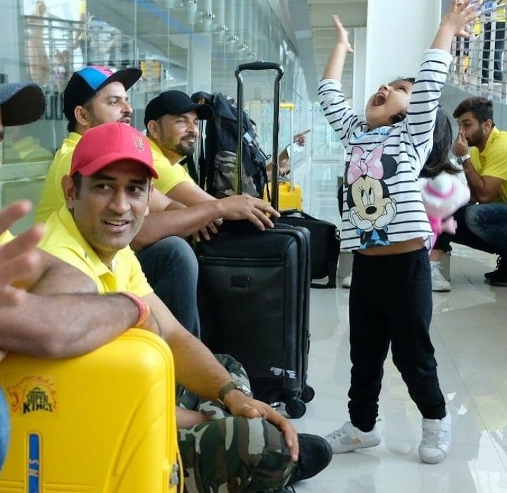 a group of people sitting around with luggage in hand and one person waving at the camera