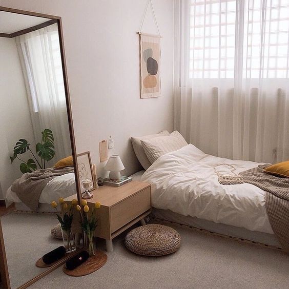 a bed room with a neatly made bed and a mirror