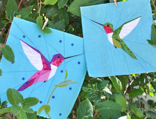 two paper hummingbirds hanging from a tree