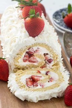 a cake with white frosting and strawberries on top is cut in half to show the inside