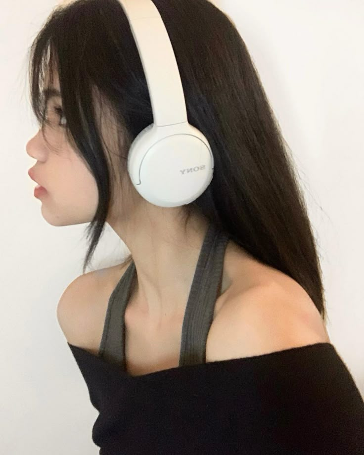 a woman with long hair wearing headphones on her ears and looking off to the side