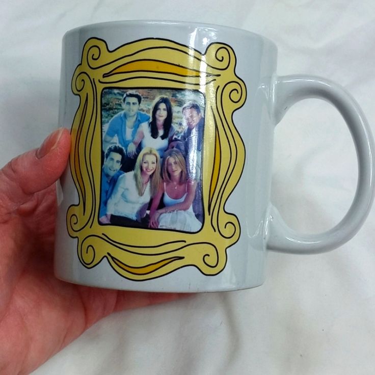 a hand holding a white coffee mug with an image of people in the frame on it