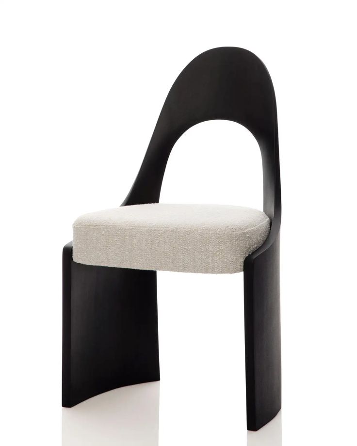 a black and white chair sitting on top of a white floor next to a wall