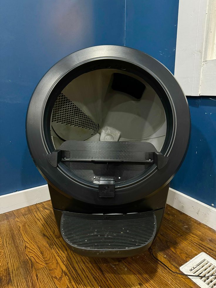 a black round object sitting on top of a wooden floor next to a blue wall