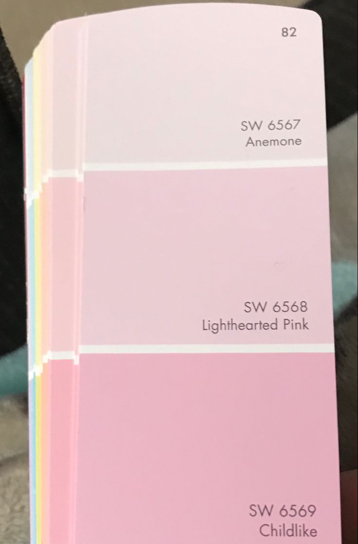 a person holding up a pink and white color swatch in front of their face