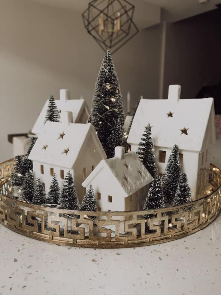 a christmas village with trees and houses in the middle is on a tray that sits on a table