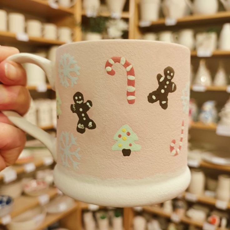 a person holding up a coffee cup with candy canes and gingerbreads on it