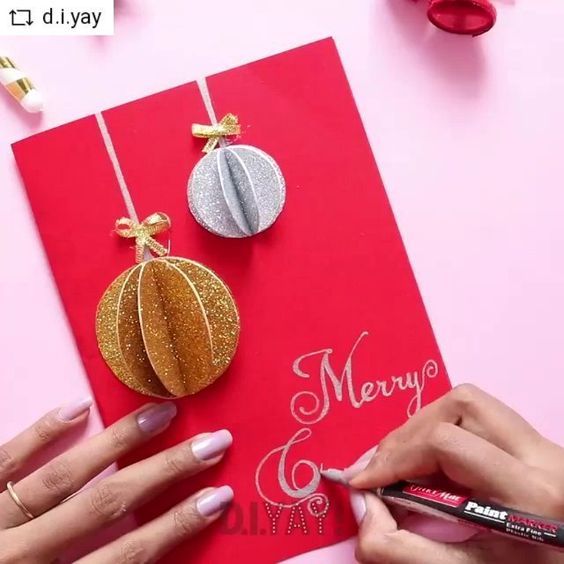 a woman is cutting out christmas decorations on a red card with gold and silver accents