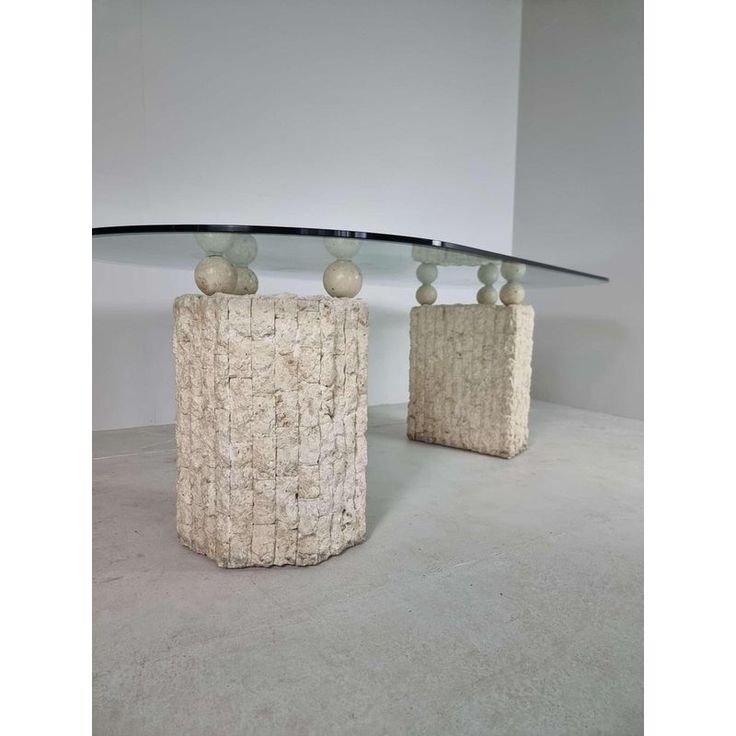 two vases sitting on top of each other in front of a glass table topped with rocks