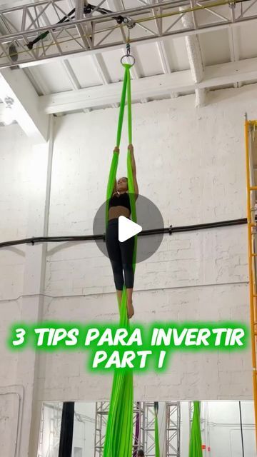 a woman is doing aerial acrobatic tricks in the gym with green ribbons