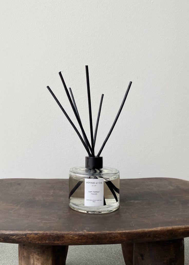 a glass jar filled with reeds sitting on top of a wooden table