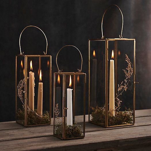 two gold lanterns with candles in them are sitting on a wooden table next to each other