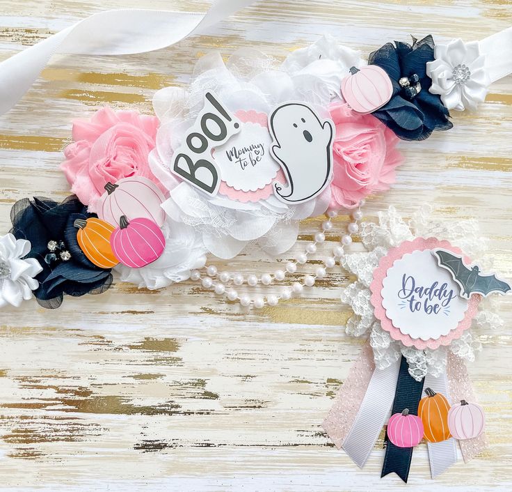 two baby headbands decorated with ribbons and paper flowers on a wooden table top