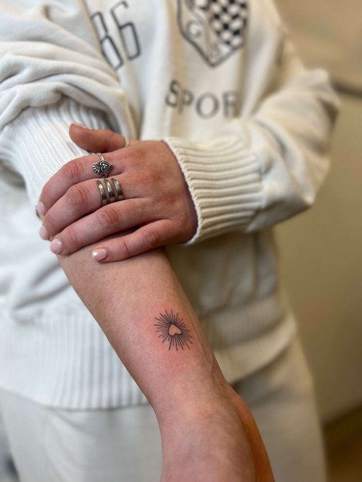 a woman with a small sun tattoo on her left arm and the other half of her arm