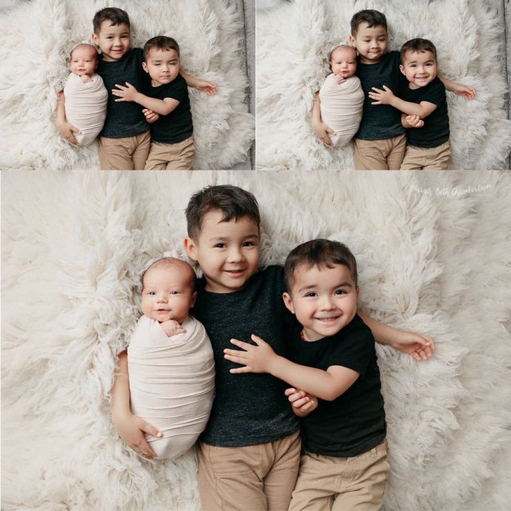 three young boys are hugging each other while laying on a fluffy white blanket and smiling at the camera