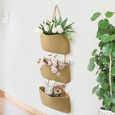 three baskets with flowers and stuffed animals are hanging on the wall next to a potted plant