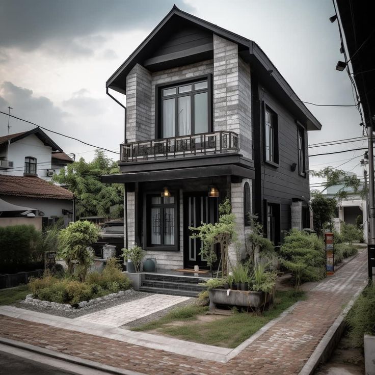 a black and white house with lots of plants on the front yard, in an urban area