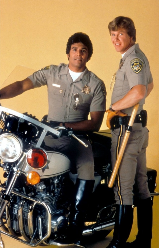 two police officers sitting on a motorcycle posing for a photo with the officer behind them