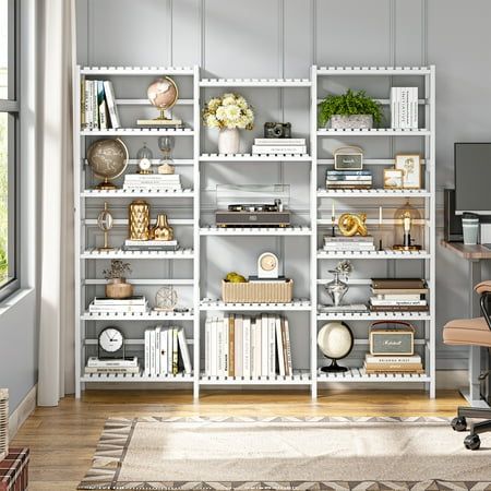 a white bookcase with many books on it in a living room next to a window