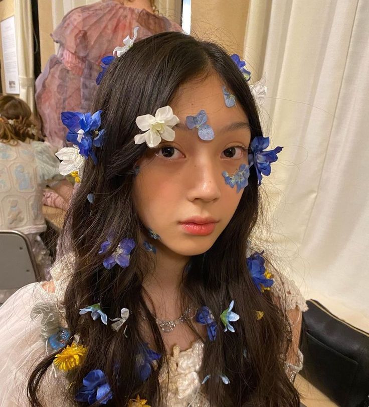 a girl with blue and white flowers in her hair