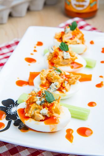 several deviled eggs are arranged on a white platter with garnishes